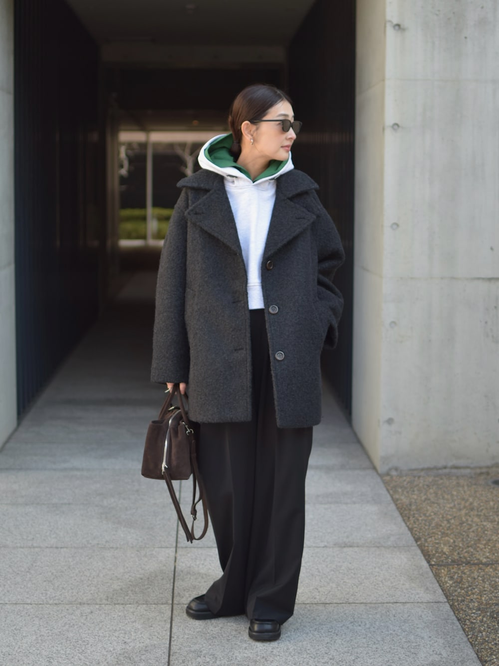 グレー系のパーカー、ブラック系のその他アウター、ブラウン系のトートバッグを着用したレディースの冬コーディネートの4枚目の写真