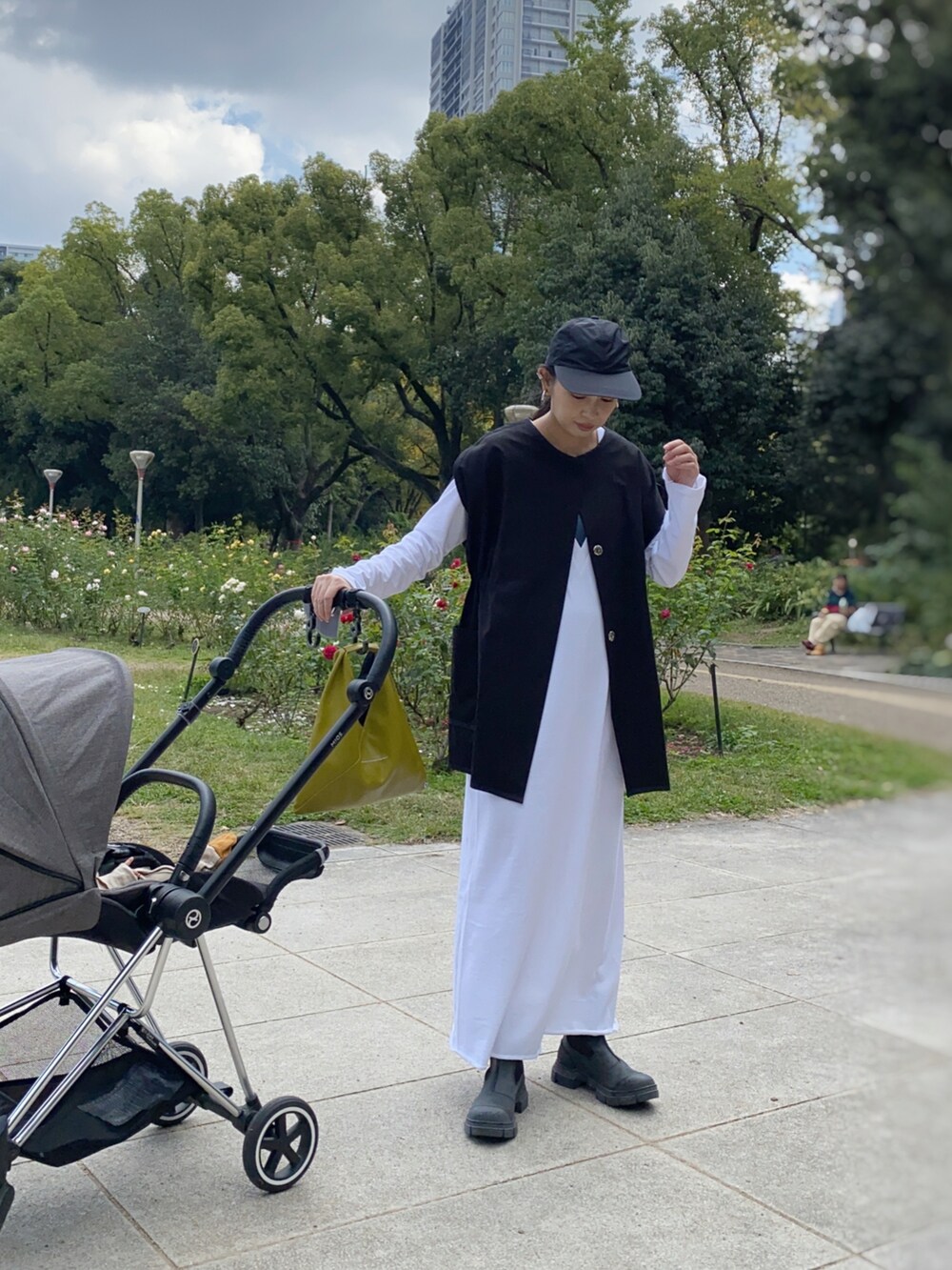 ブラック系のベスト、ホワイト系のワンピース、イエロー系のハンドバッグを着用したレディースの秋コーディネートの2枚目の写真