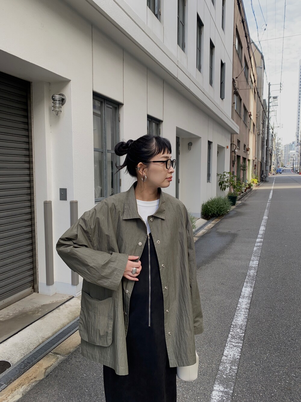 グリーン系のナイロンジャケット、ブラック系のジャンパースカート、ブラック系のブーツを着用したレディースの冬コーディネートの2枚目の写真