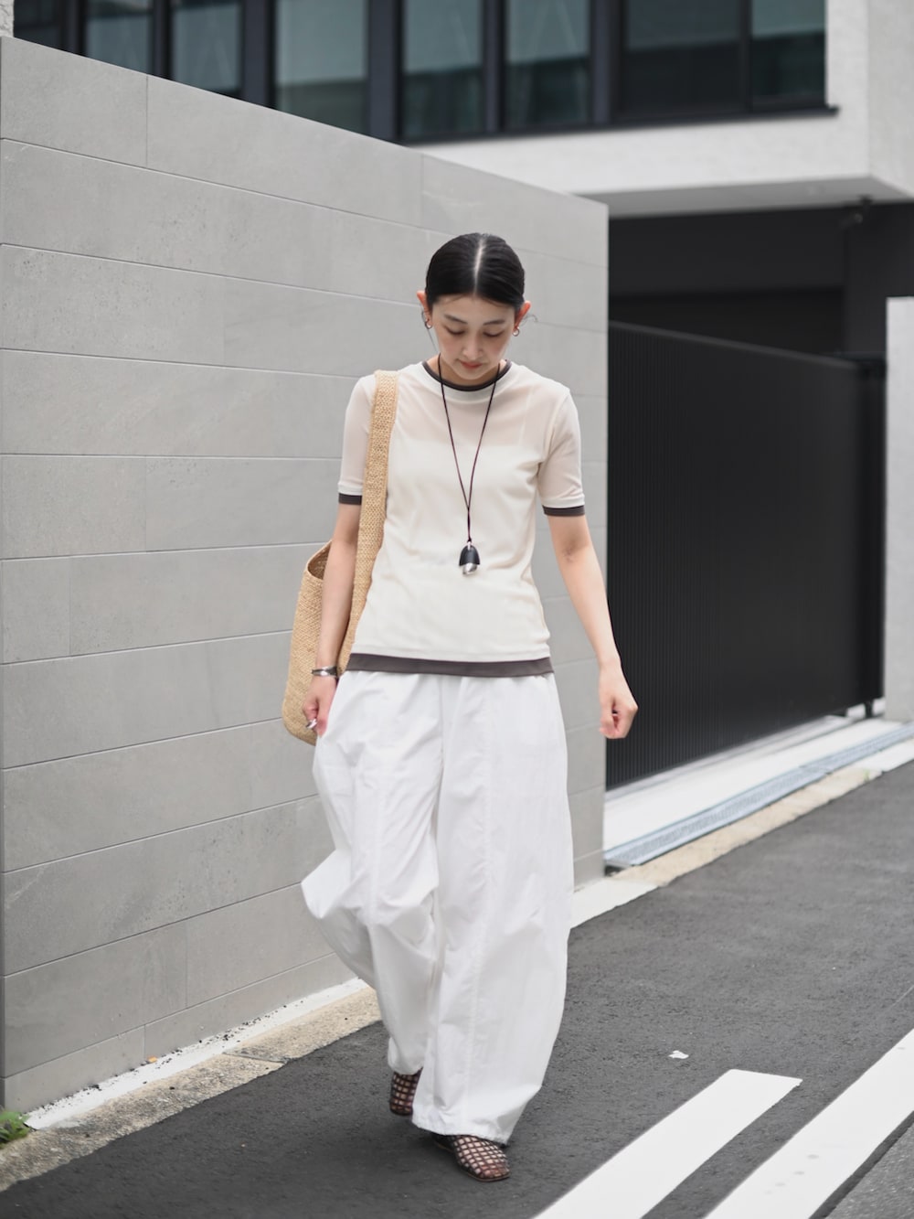 ホワイト系のTシャツ/カットソー、ベージュ系のかごバッグ、ブラウン系のバレエシューズを着用したレディースの夏コーディネートの4枚目の写真