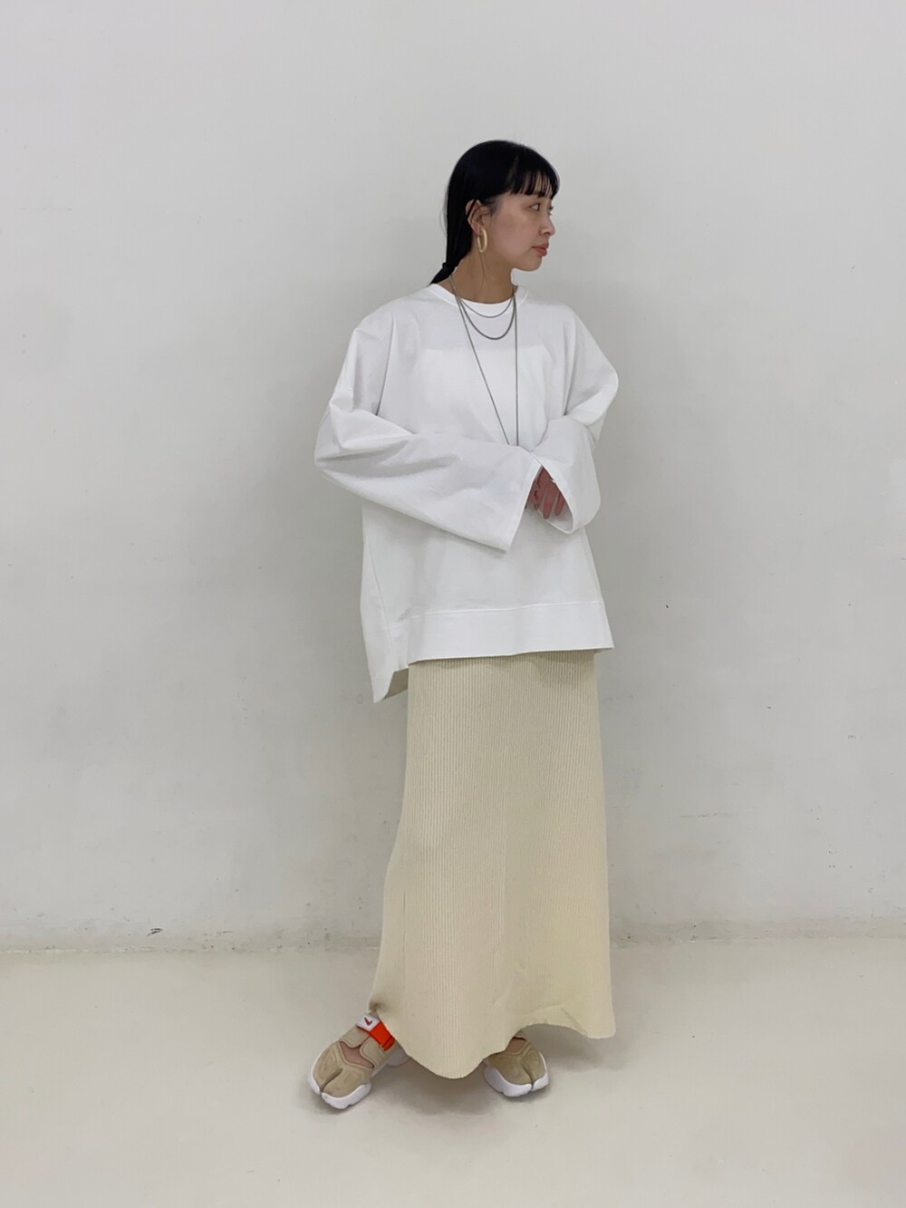 ホワイト系のスカート、その他のスニーカー、シルバー系のネックレスを着用したレディースの春コーディネートの2枚目の写真