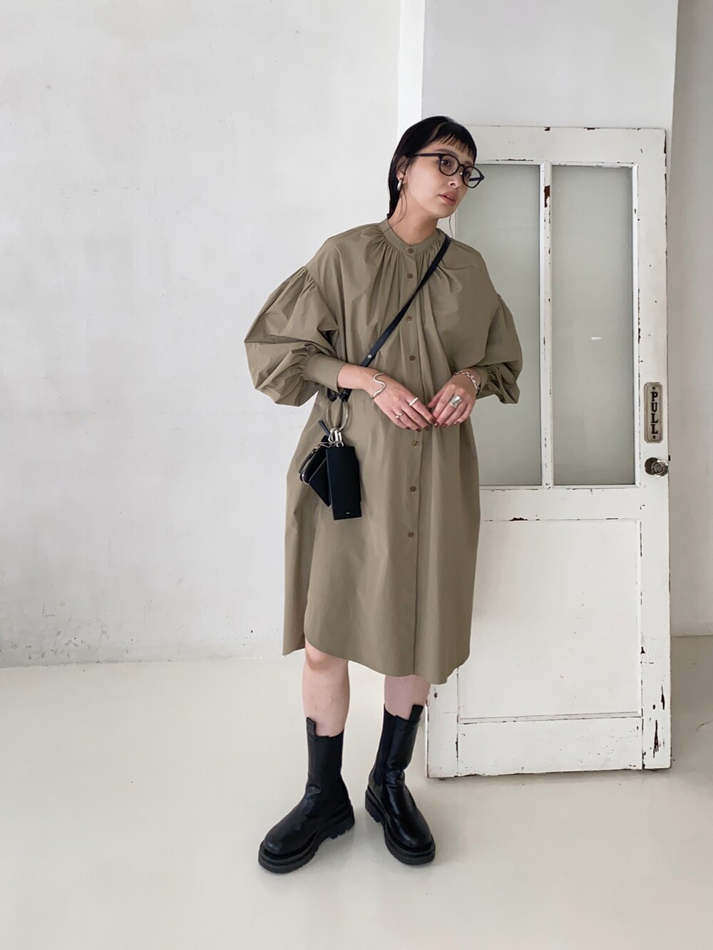 ブラック系のショルダーバッグ、グリーン系のシャツワンピースを着用したレディースの秋コーディネートの3枚目の写真