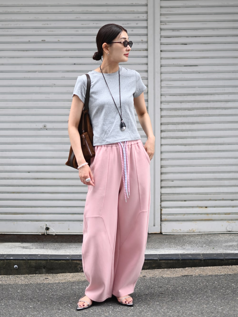 ピンク系のスウェットパンツ、グレー系のTシャツ/カットソー、ブラウン系のトートバッグを着用したレディースの夏コーディネートの4枚目の写真