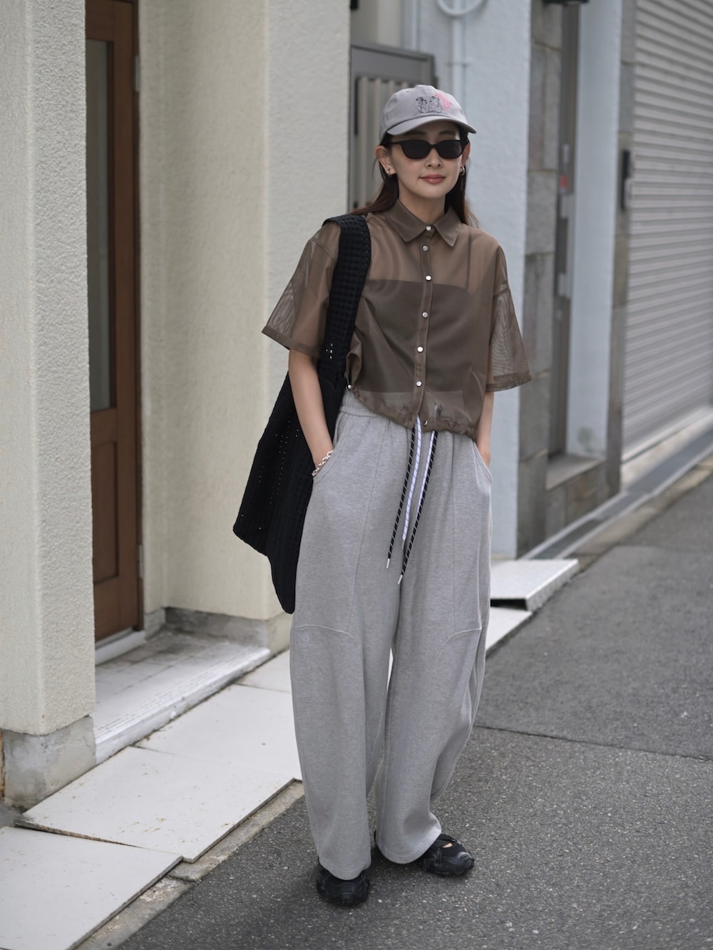 グレー系のスウェットパンツ、ブラック系のトートバッグ、グレー系のキャップを着用したレディースの夏コーディネートの3枚目の写真
