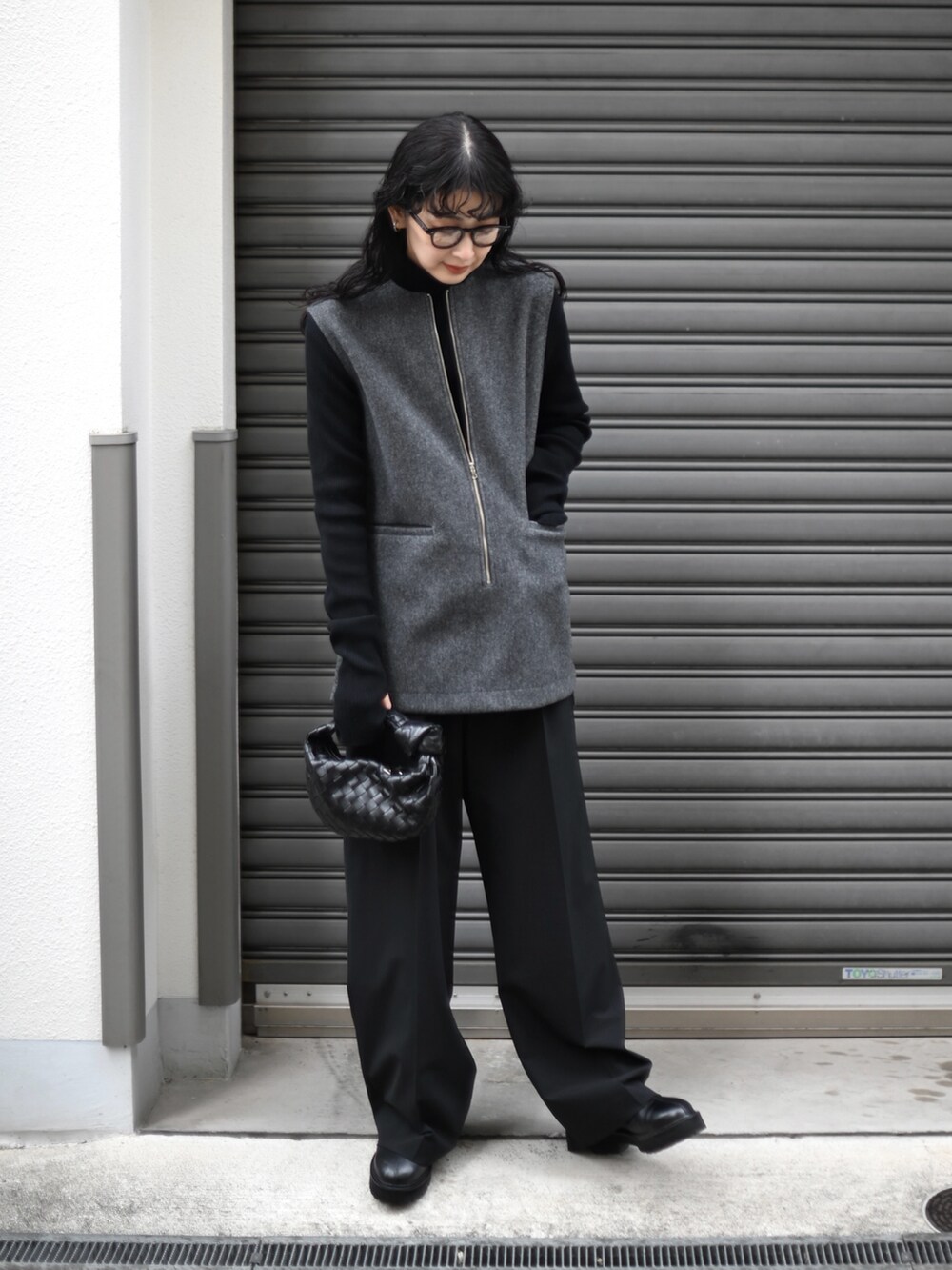 グレー系のベスト、ブラック系のスラックス、ブラック系のブーツを着用したレディースの冬コーディネートの5枚目の写真