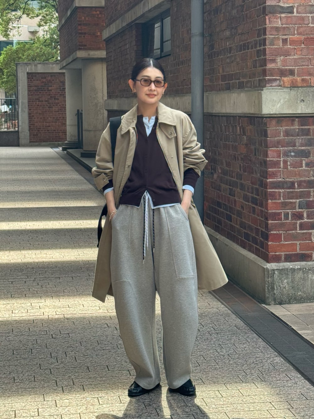 ブラック系のトートバッグ、ベージュ系のステンカラーコート、ブルー系のカーディガン/ボレロを着用したレディースの春コーディネートの4枚目の写真