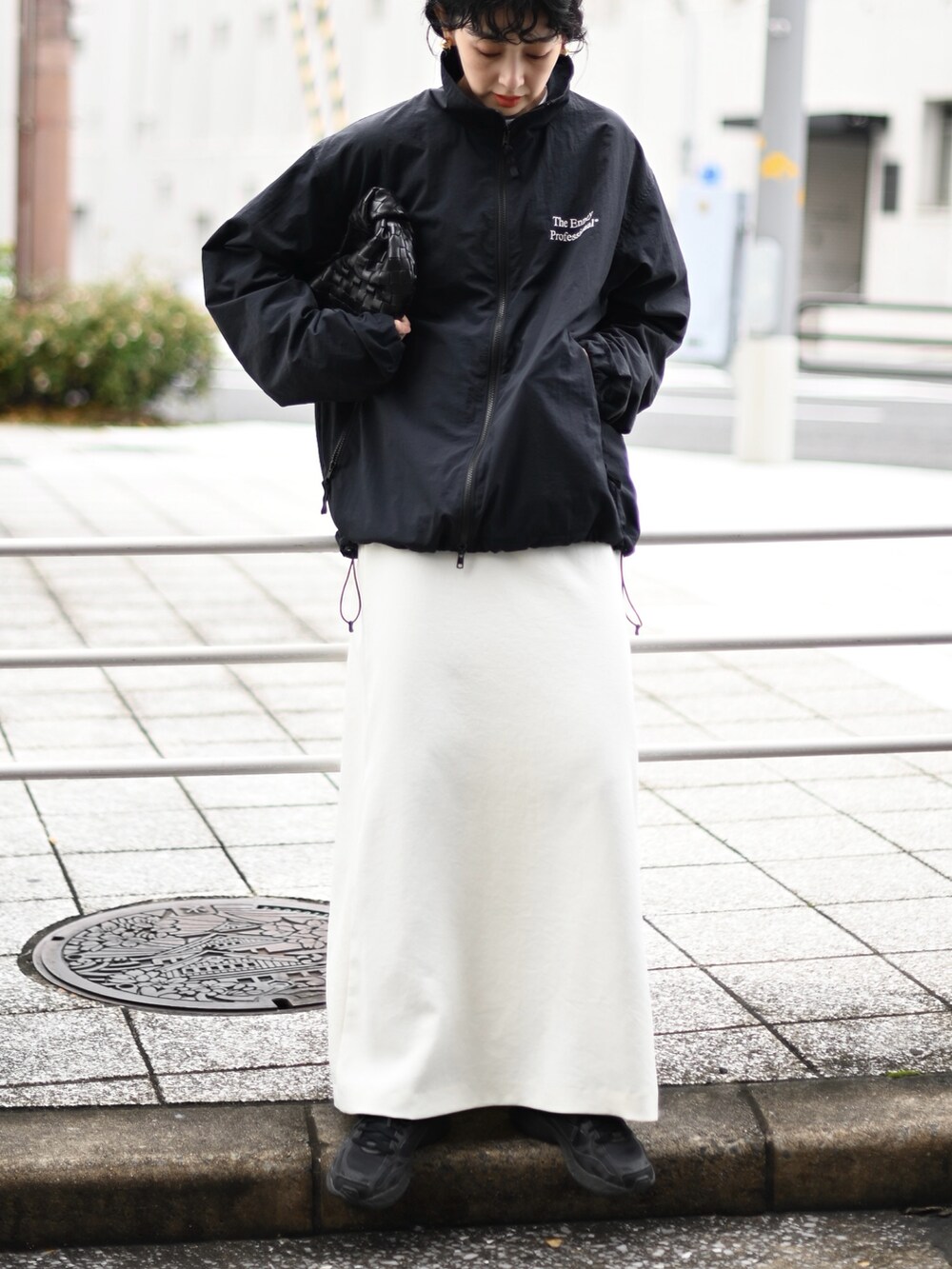 ブラック系のナイロンジャケット、ホワイト系のスカート、ブラック系のスニーカーを着用したレディースの冬コーディネートの3枚目の写真