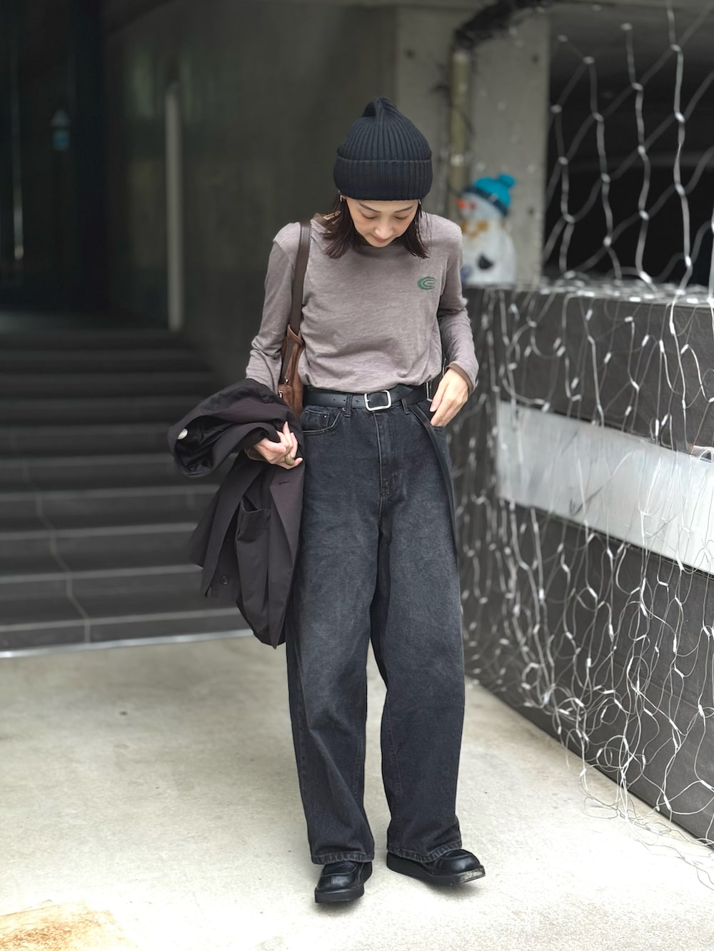 グレー系のTシャツ/カットソー、ブラック系のデニムパンツ、ブラウン系のショルダーバッグを着用したレディースの秋コーディネートの3枚目の写真