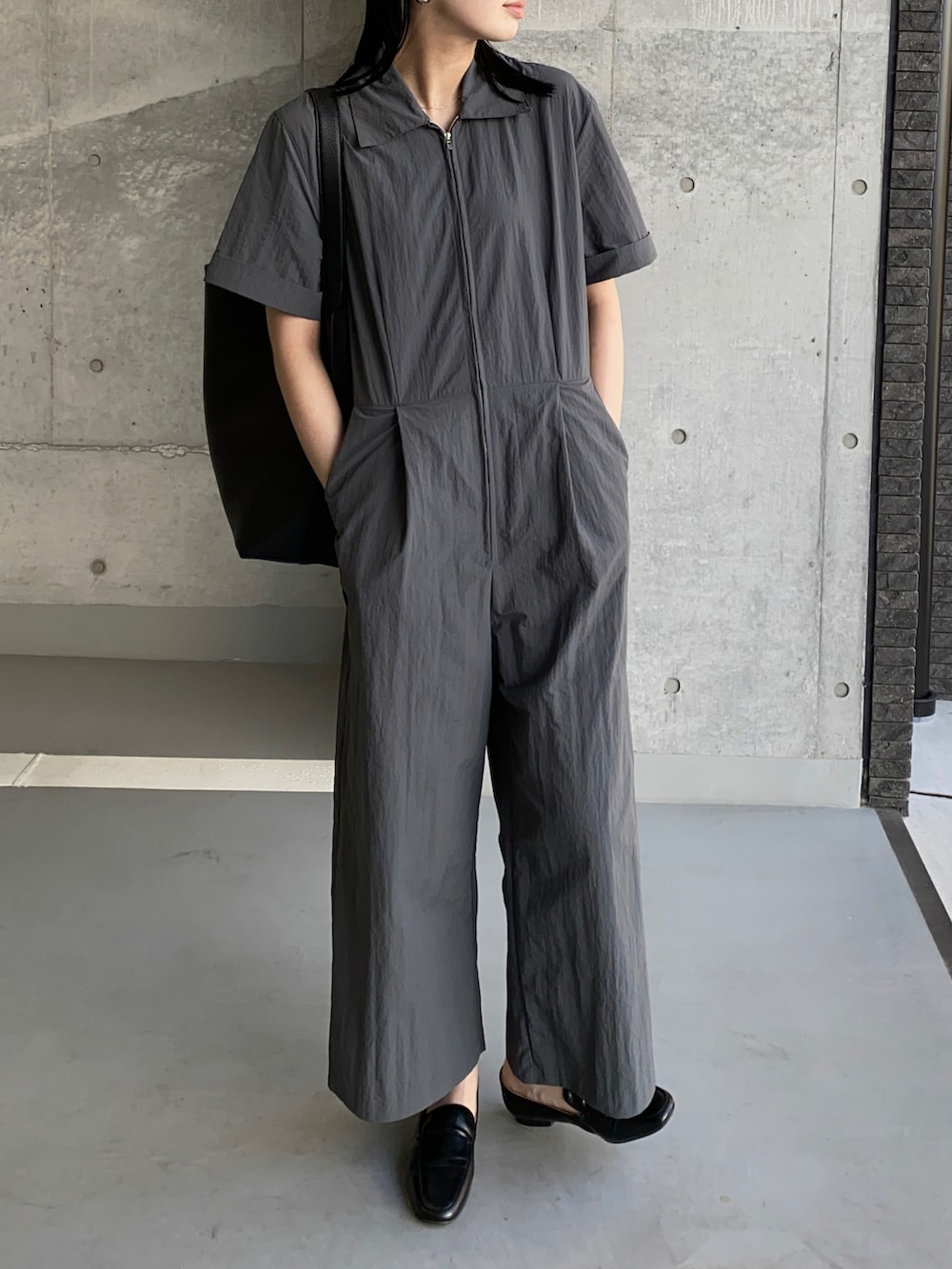 グレー系のつなぎ/オールインワン、ブラック系のショルダーバッグ、シルバー系のイヤリングを着用したレディースの秋コーディネートの2枚目の写真