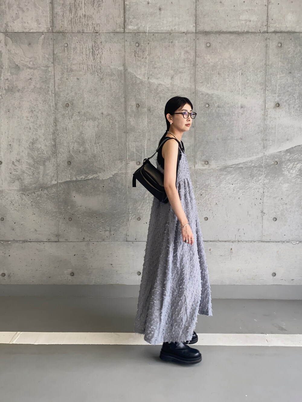 グレー系のワンピース、ブラック系のショルダーバッグ、ブラック系のメガネを着用したレディースの夏コーディネートの3枚目の写真