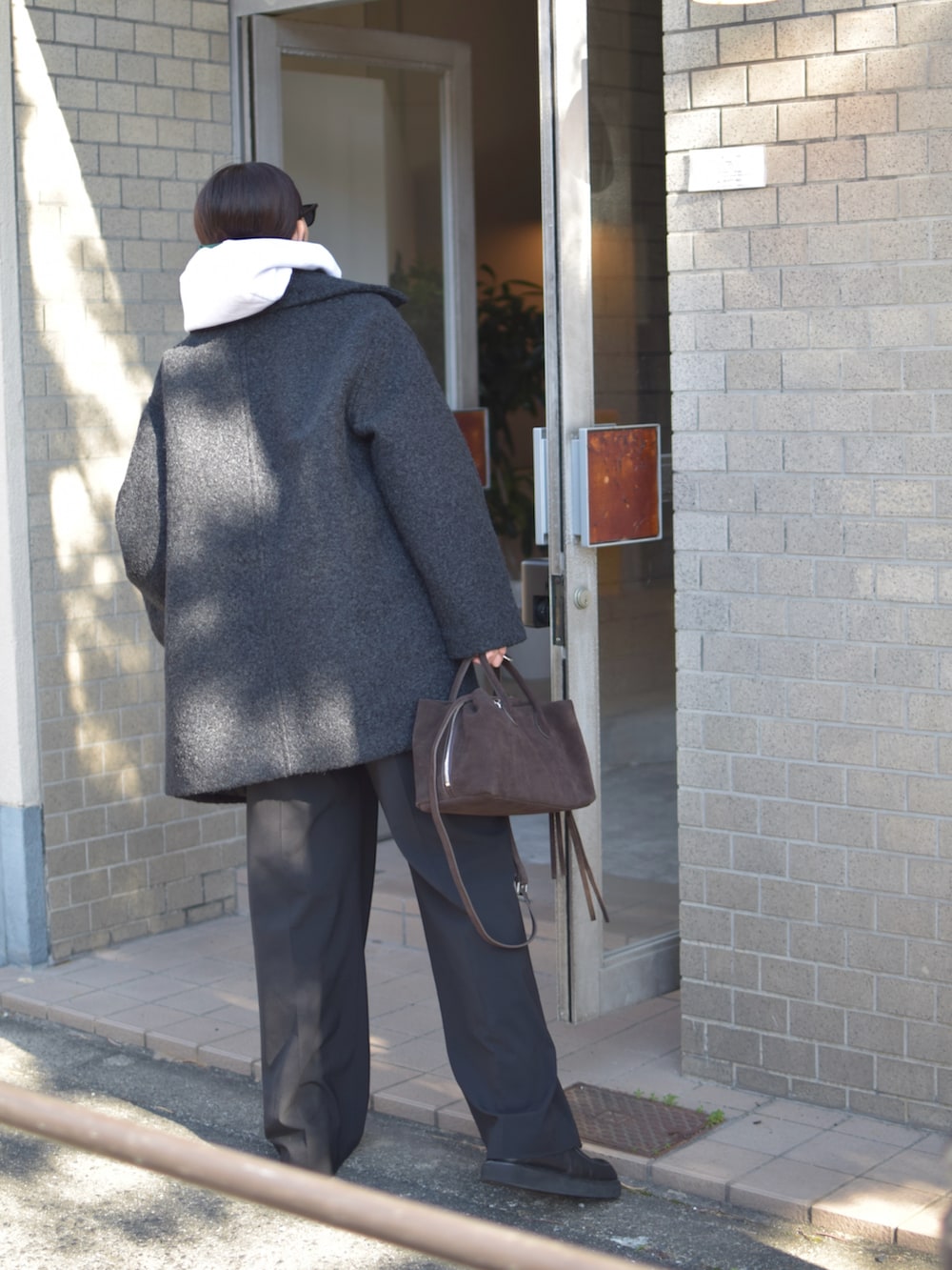 グレー系のパーカー、ブラック系のその他アウター、ブラウン系のトートバッグを着用したレディースの冬コーディネートの3枚目の写真