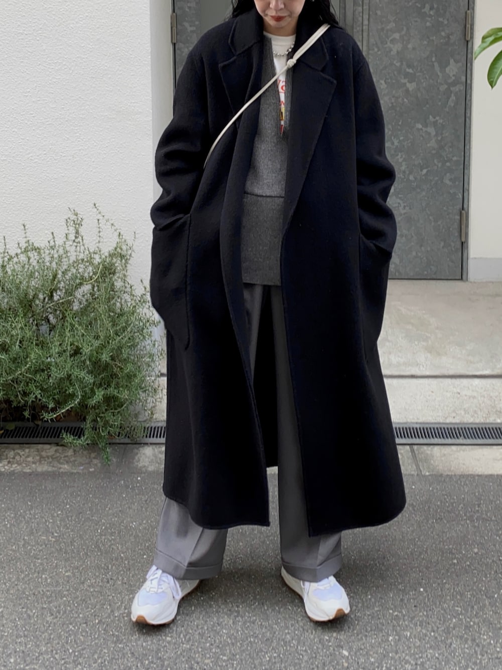 ブラック系のチェスターコート、ホワイト系のスニーカー、グレー系のキャップを着用したレディースの冬コーディネートの3枚目の写真