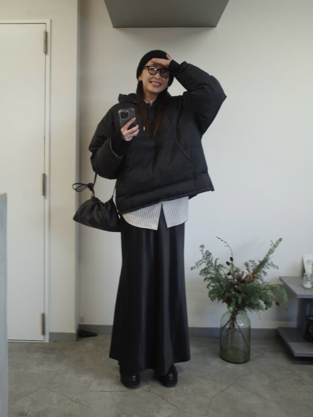 ブラック系のダウンジャケット/コート、ブラック系のブーツ、ブラック系のスカートを着用したレディースの冬コーディネートの3枚目の写真