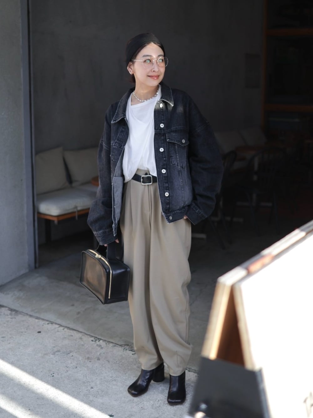 ブラック系のデニムジャケット、ブラック系のハンドバッグ、ブラック系のブーツを着用したレディースの冬コーディネートの5枚目の写真