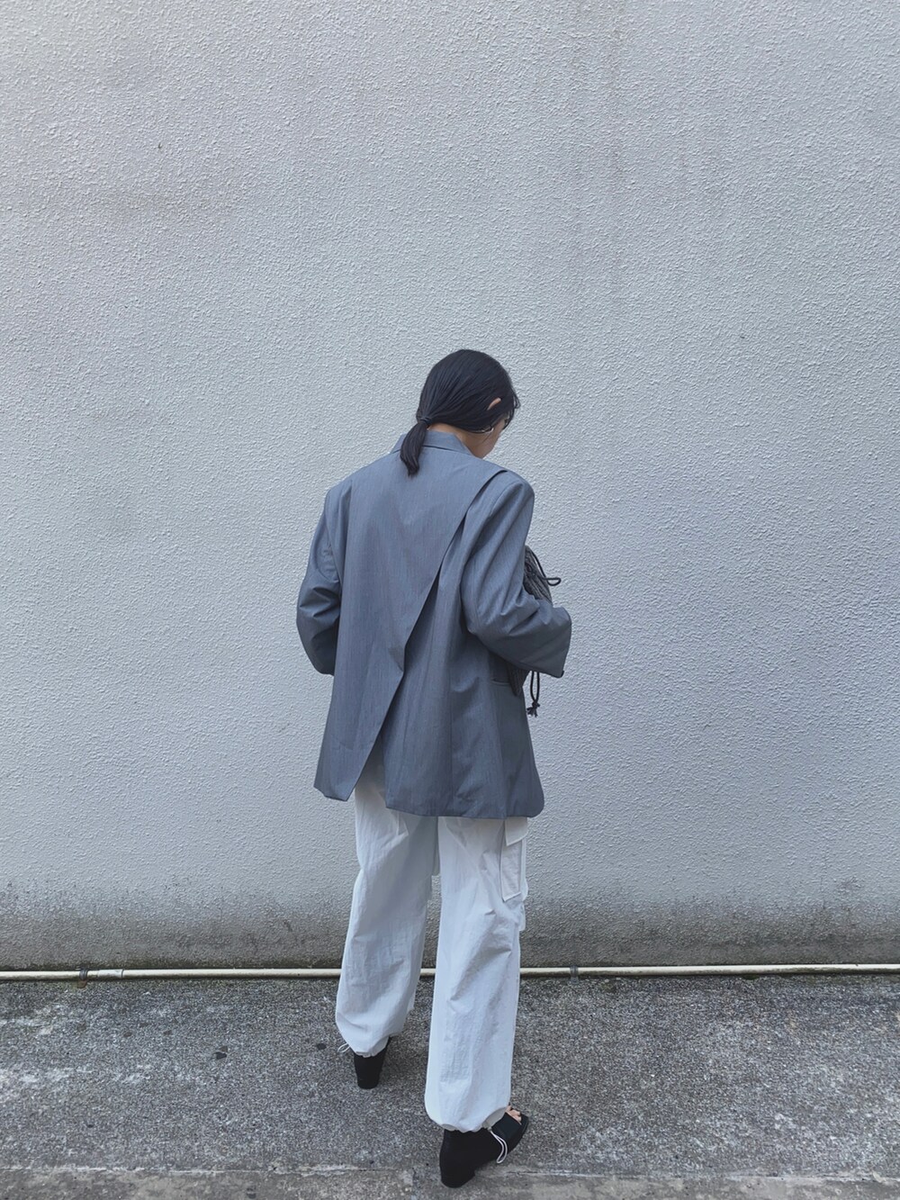 グレー系のテーラードジャケット、ホワイト系のカーゴパンツ、シルバー系のネックレスを着用したレディースの春コーディネートの3枚目の写真