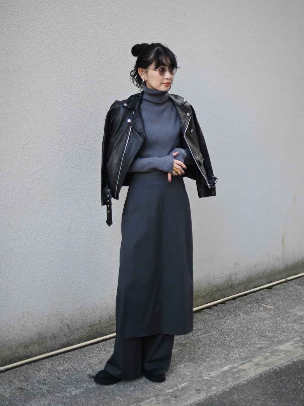 グレー系のニット/セーター、グレー系のスラックス、ブラック系のライダースジャケットを着用したレディースの秋コーディネートの5枚目の写真