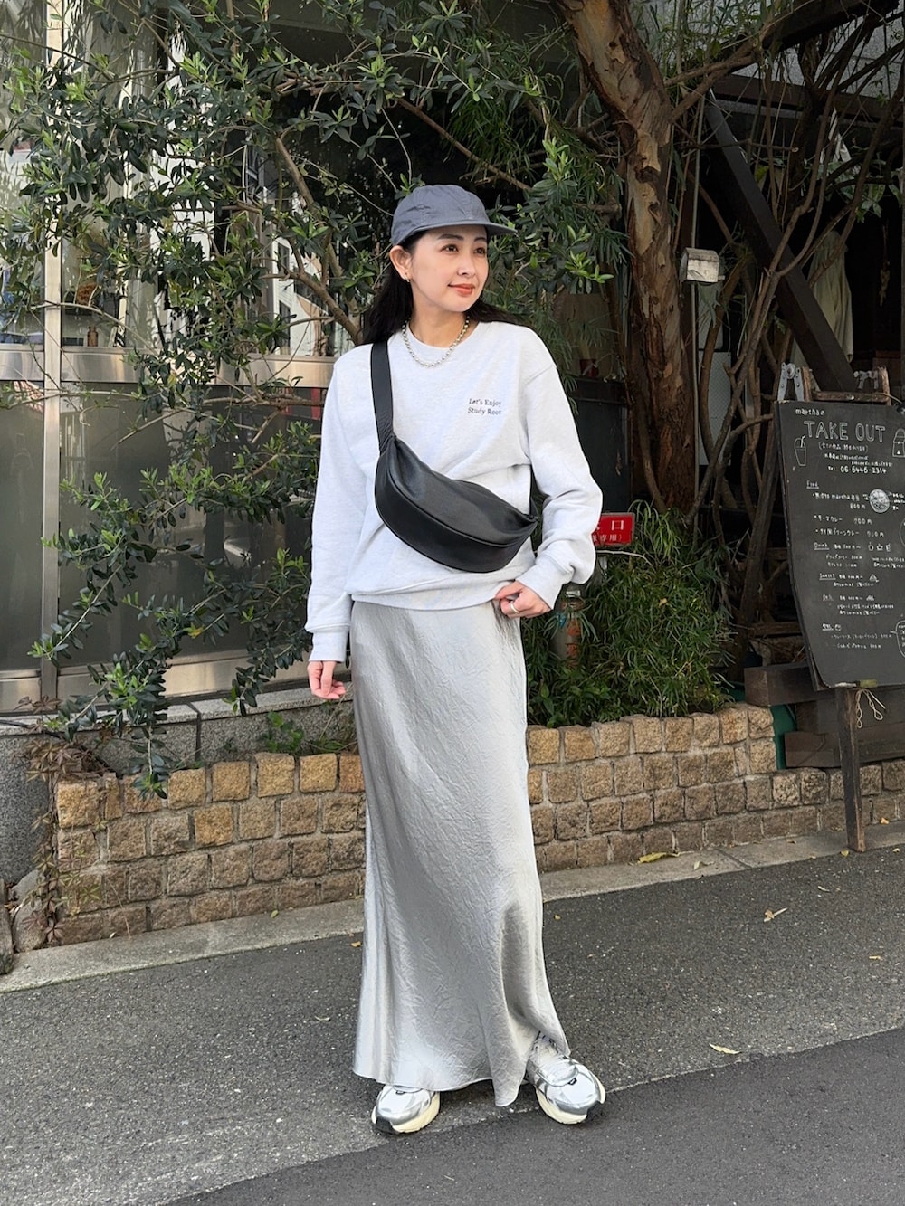 グレー系のスウェット、シルバー系のスカート、ホワイト系のスニーカーを着用したレディースの春コーディネートの2枚目の写真