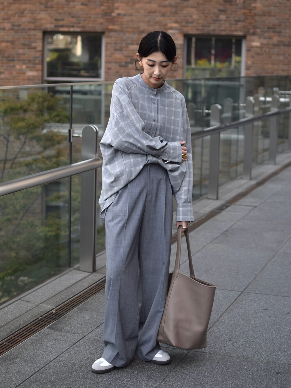 グレー系のシャツ/ブラウス、グレー系のスラックス、ベージュ系のショルダーバッグを着用したレディースの秋コーディネートの2枚目の写真