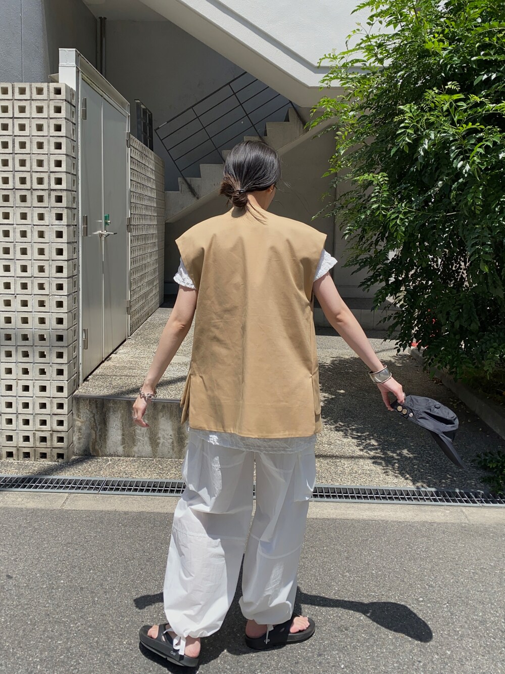 ベージュ系のベスト、ブラック系のサンダル、ブラック系のキャップを着用したレディースの秋コーディネートの3枚目の写真