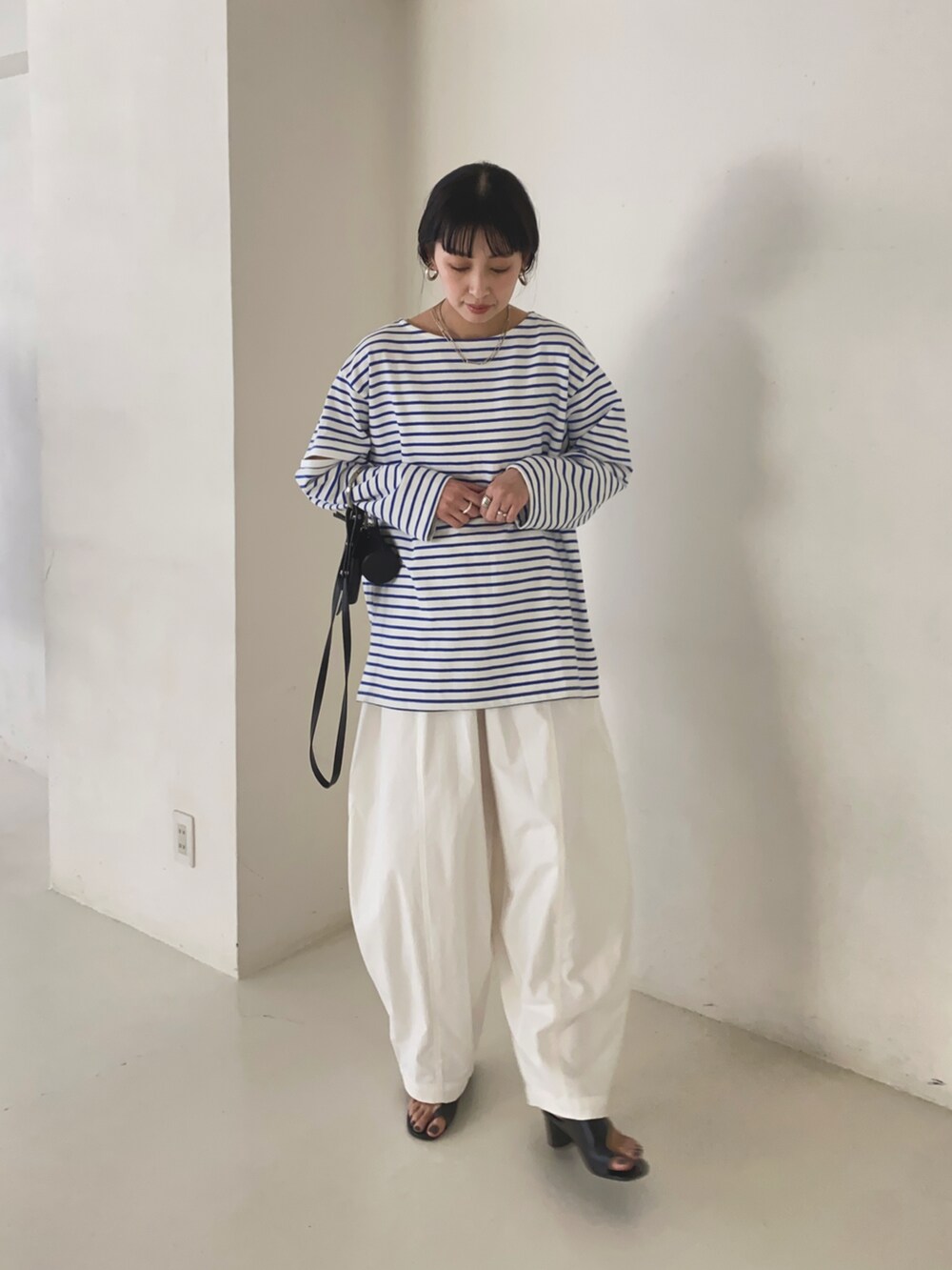 ブルー系のTシャツ/カットソー、ホワイト系のチノパンツ、ブラック系のショルダーバッグを着用したレディースの春コーディネートの3枚目の写真