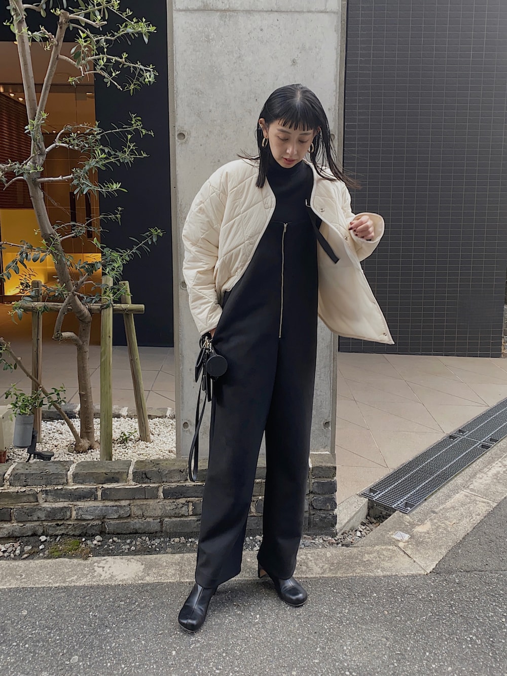 ホワイト系のダウンジャケット/コート、ブラック系のサロペット/オーバーオール、ブラック系のニット/セーターを着用したレディースの冬コーディネートの3枚目の写真