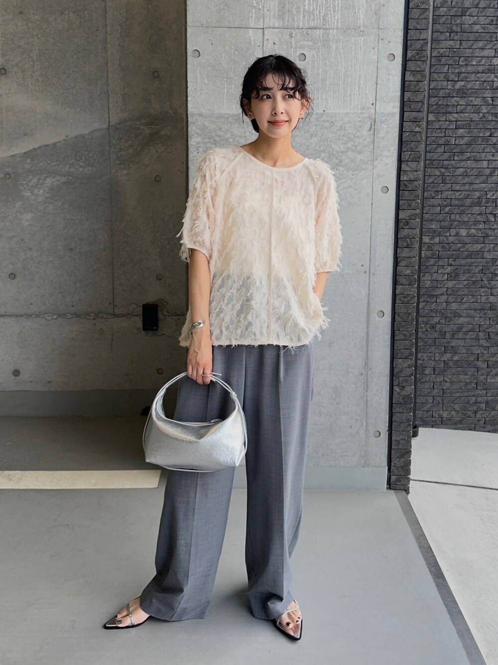 ホワイト系のシャツ/ブラウス、シルバー系のサンダル、グレー系のスラックスを着用したレディースの夏コーディネートの2枚目の写真