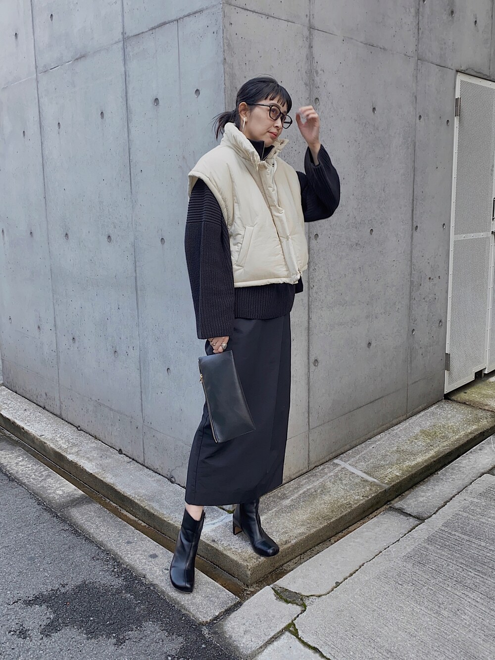 ホワイト系のダウンベスト、ブラック系のニット/セーター、ブラック系のスカートを着用したレディースの冬コーディネートの3枚目の写真