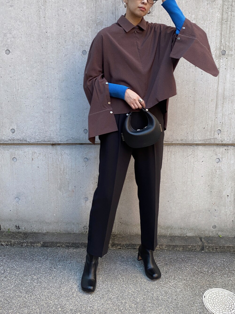 ブラック系のシャツ/ブラウス、ブルー系のニット/セーター、ブラック系のハンドバッグを着用したレディースの秋コーディネートの2枚目の写真