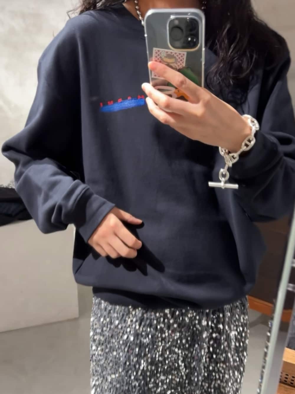 ブルー系のスウェット、シルバー系のスカート、ブラック系のブーツを着用したレディースの秋コーディネートの2枚目の写真