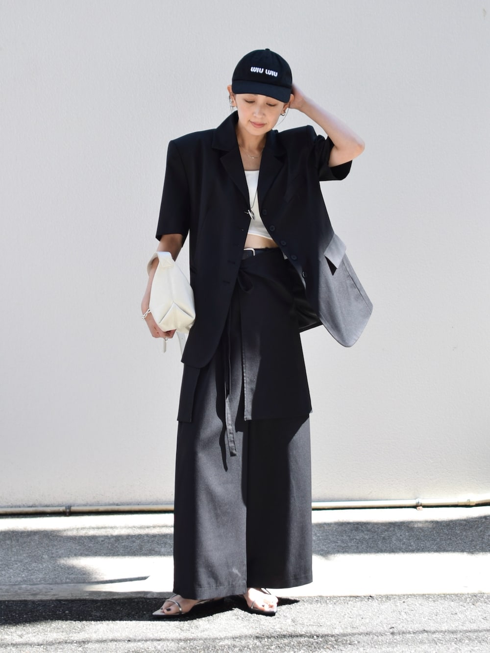 ブラック系のテーラードジャケット、ブラック系のスラックス、ホワイト系のショルダーバッグを着用したレディースの春コーディネートの2枚目の写真