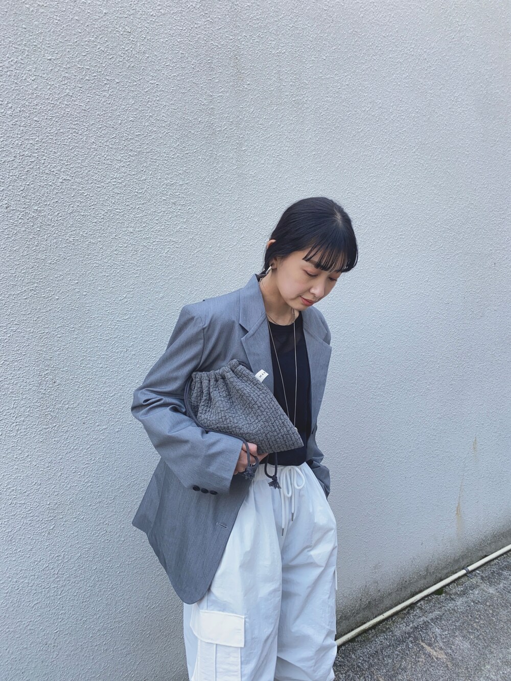 グレー系のテーラードジャケット、ホワイト系のカーゴパンツ、シルバー系のネックレスを着用したレディースの春コーディネートの4枚目の写真