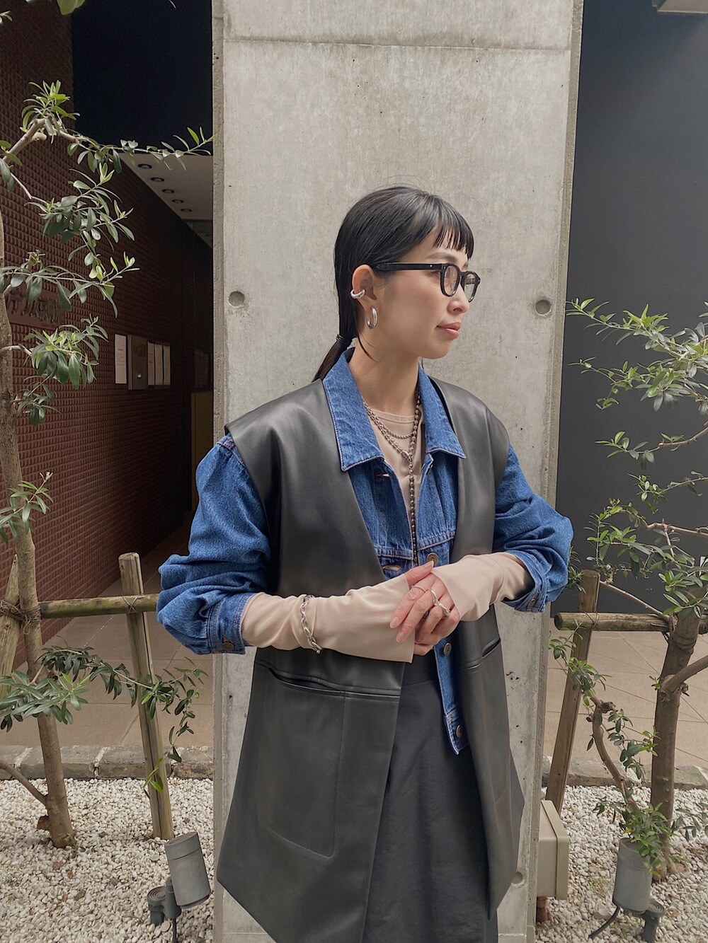 ブルー系のデニムジャケット、ブラック系のベスト、ベージュ系のTシャツ/カットソーを着用したレディースの冬コーディネートの2枚目の写真