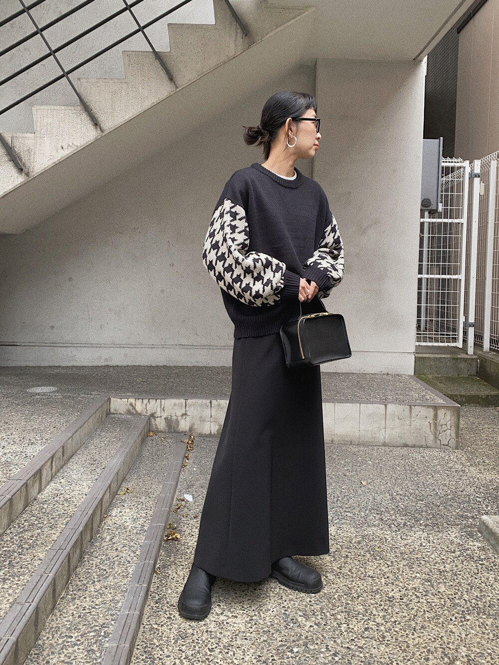 ブラック系のニット/セーター、ブラック系のダウンベスト、ブラック系のスカートを着用したレディースの冬コーディネートの4枚目の写真