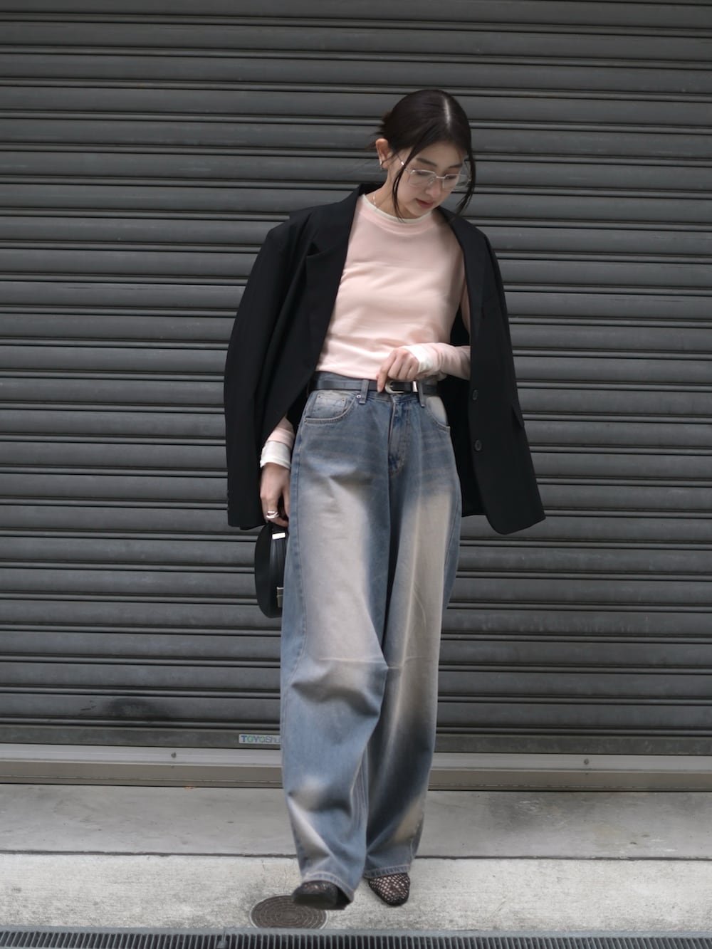 ピンク系のTシャツ/カットソー、ブラック系のハンドバッグ、ブルー系のデニムパンツを着用したレディースの春コーディネートの2枚目の写真