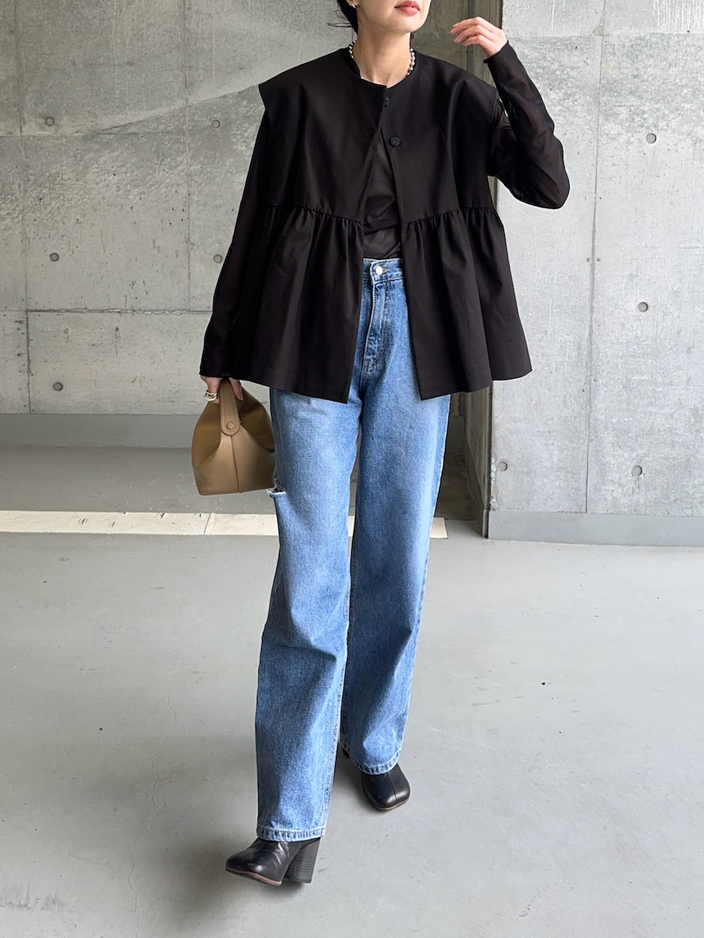 ブラック系のベスト、ブラック系のTシャツ/カットソー、ブルー系のデニムパンツを着用したレディースの春コーディネートの2枚目の写真