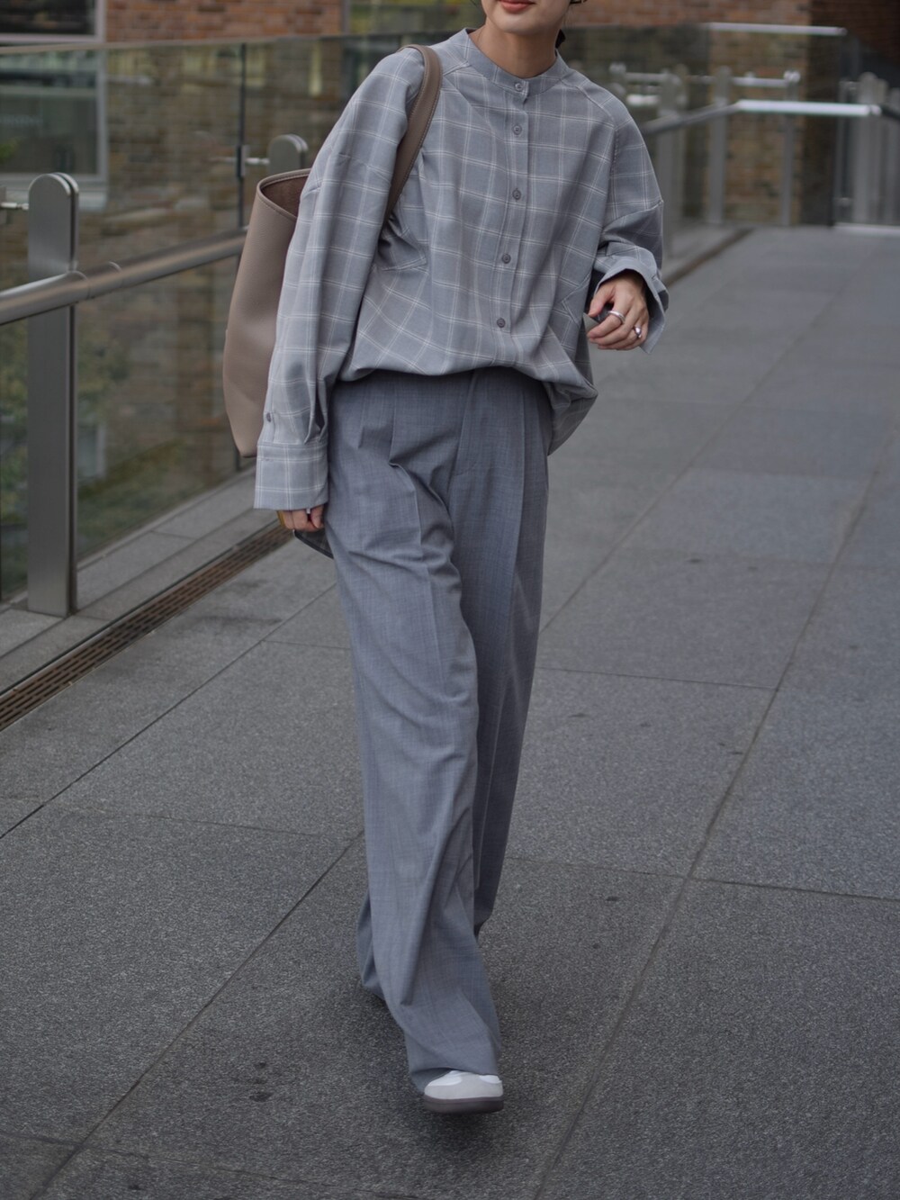 グレー系のシャツ/ブラウス、グレー系のスラックス、ベージュ系のショルダーバッグを着用したレディースの秋コーディネートの3枚目の写真