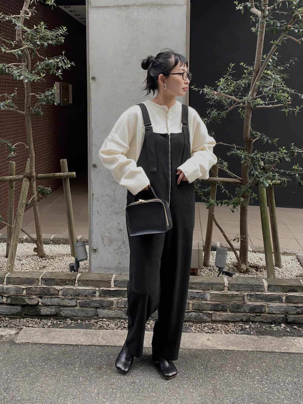 ブラック系のサロペット/オーバーオール、ホワイト系のニット/セーター、ブラック系のブーツを着用したレディースの冬コーディネートの2枚目の写真