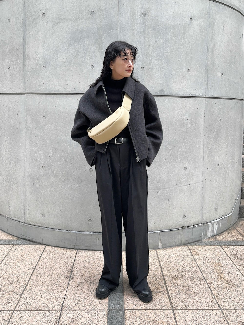 グレー系のブルゾン、ブラック系のスラックス、ブラック系のブーツを着用したレディースの冬コーディネートの2枚目の写真