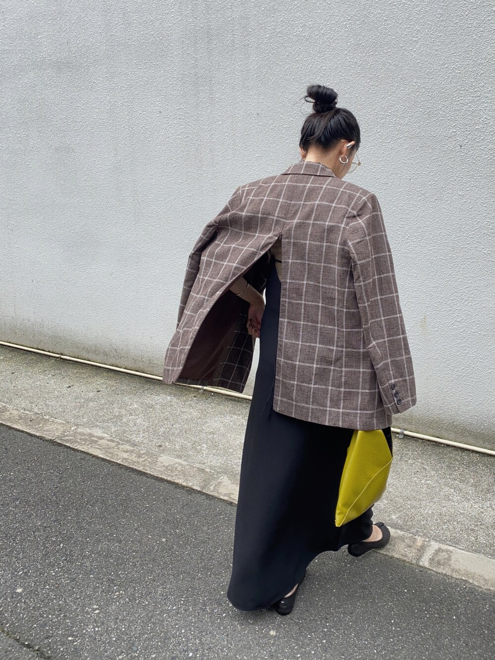 ブラウン系のテーラードジャケット、ブラック系のワンピース、イエロー系のハンドバッグを着用したレディースの秋コーディネートの3枚目の写真