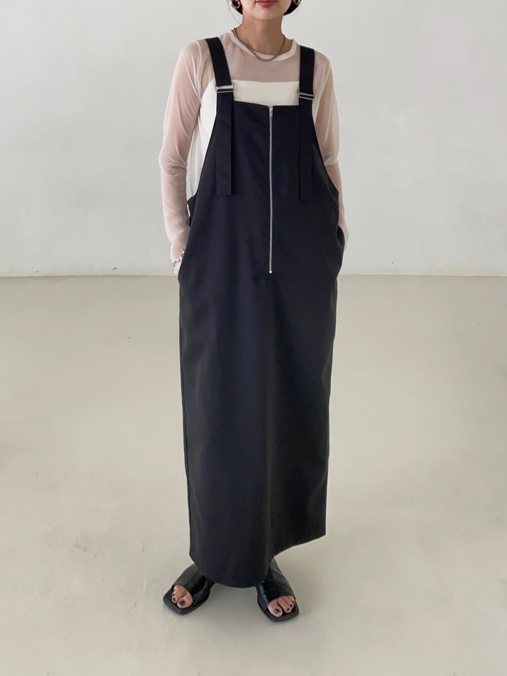 ブラック系のジャンパースカート、ホワイト系のTシャツ/カットソー、ホワイト系のキャミソールを着用したレディースの夏コーディネートの2枚目の写真