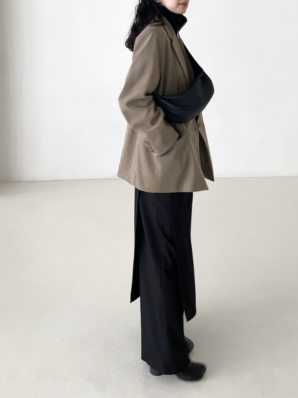 ベージュ系のテーラードジャケット、ブラック系のベスト、ブラック系のショルダーバッグを着用したレディースの冬コーディネートの3枚目の写真