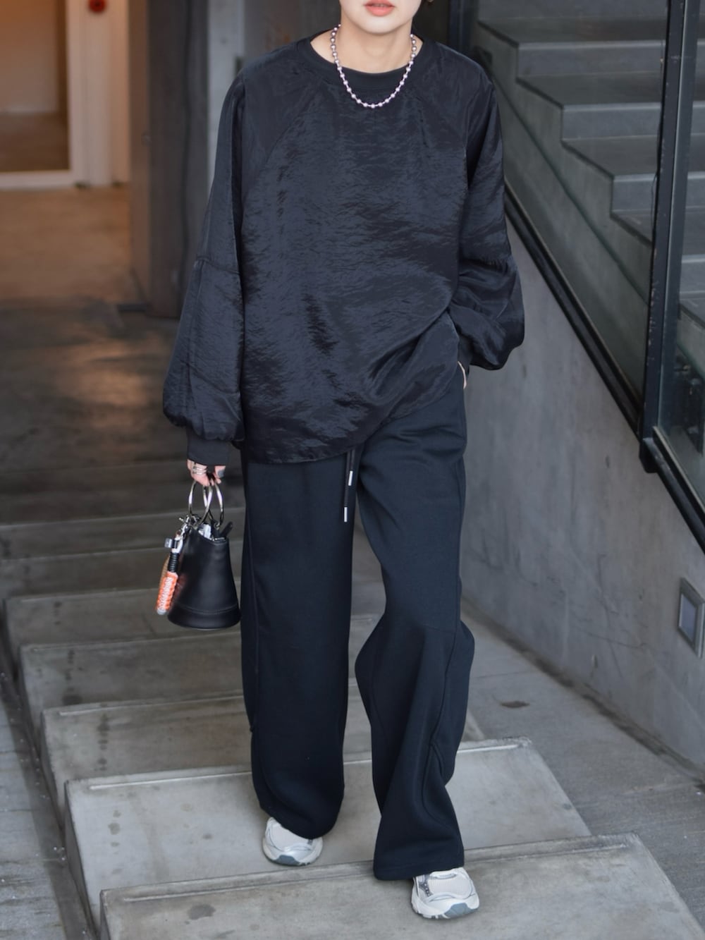 ブラック系のTシャツ/カットソー、ブラック系のスウェットパンツ、シルバー系のスニーカーを着用したレディースの春コーディネートの4枚目の写真