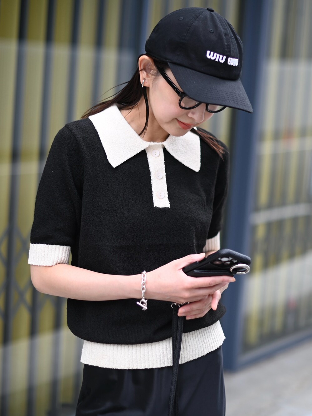 ブラック系のニット/セーター、ブラック系のスカート、ブラック系のスニーカーを着用したレディースの春コーディネートの3枚目の写真