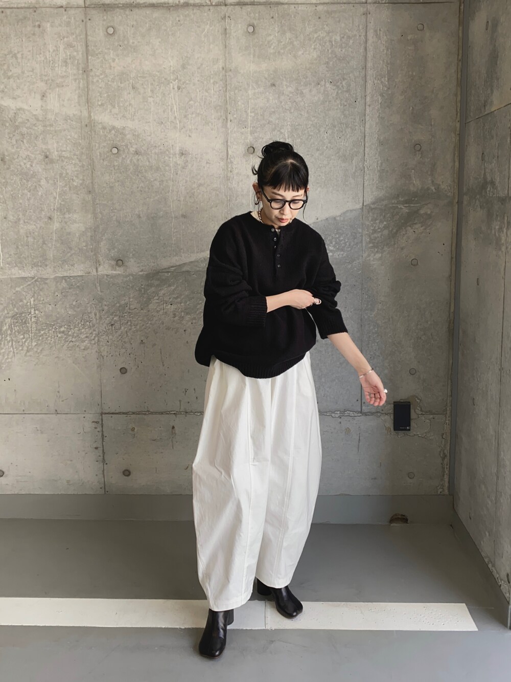 ブラック系のニット/セーター、ホワイト系のチノパンツ、ブラック系のブーツを着用したレディースの秋コーディネートの3枚目の写真