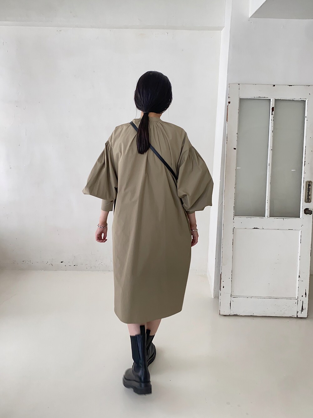 ブラック系のショルダーバッグ、グリーン系のシャツワンピースを着用したレディースの秋コーディネートの2枚目の写真