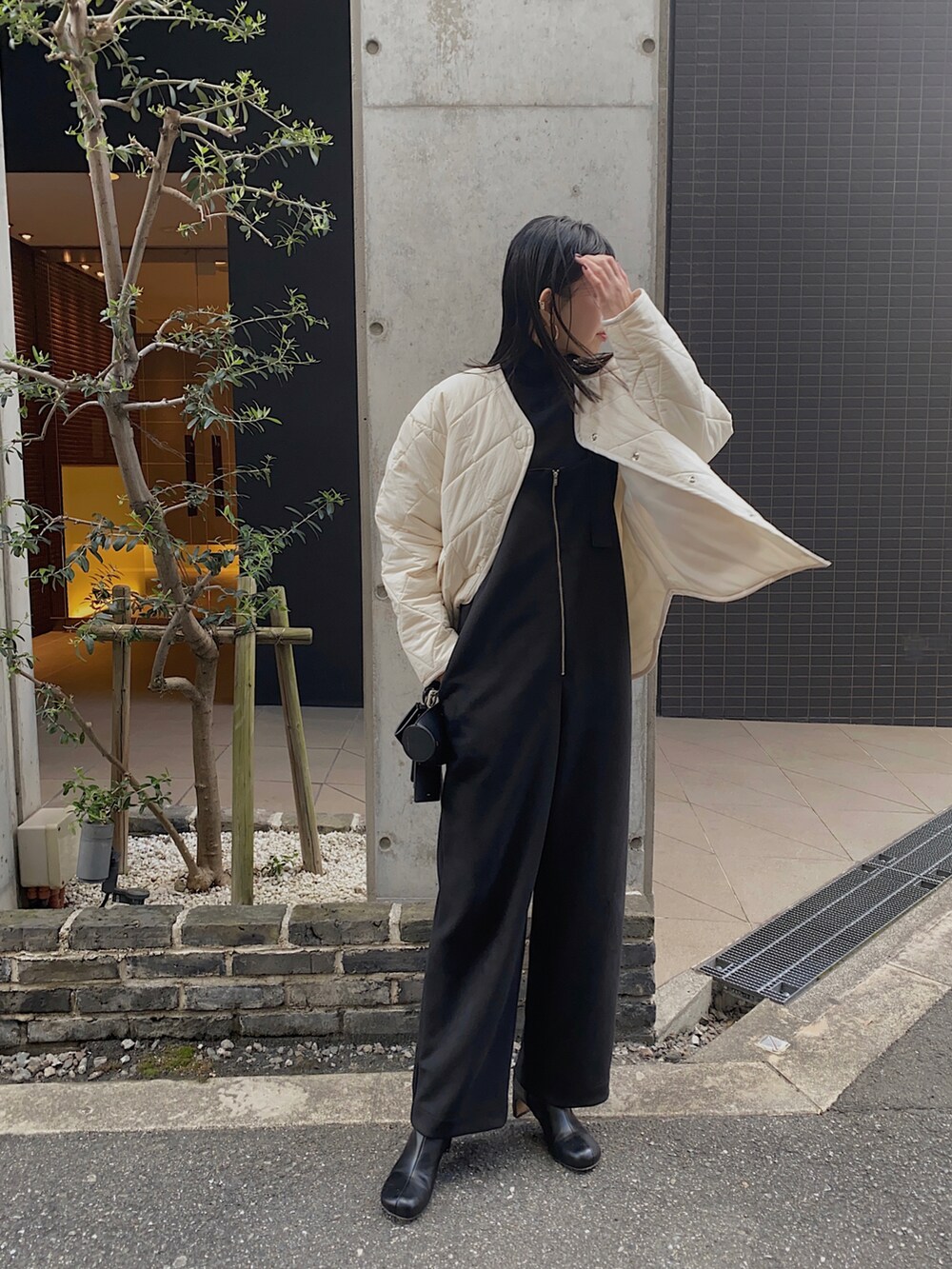 ホワイト系のダウンジャケット/コート、ブラック系のサロペット/オーバーオール、ブラック系のニット/セーターを着用したレディースの冬コーディネートの2枚目の写真
