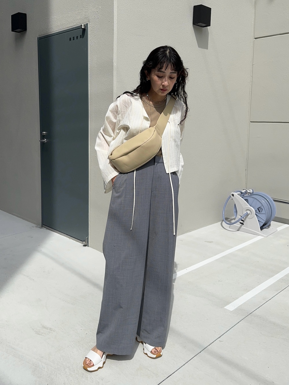 ホワイト系のシャツ/ブラウス、ベージュ系のショルダーバッグ、グレー系のスラックスを着用したレディースの春コーディネートの2枚目の写真