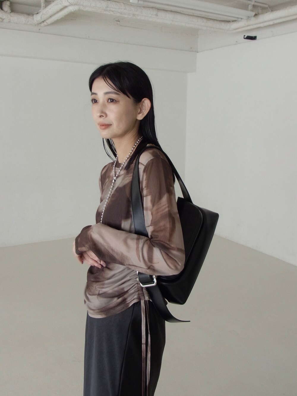 ブラウン系のTシャツ/カットソー、ブラック系のショルダーバッグ、ブラック系のスカートを着用したレディースの秋コーディネートの2枚目の写真