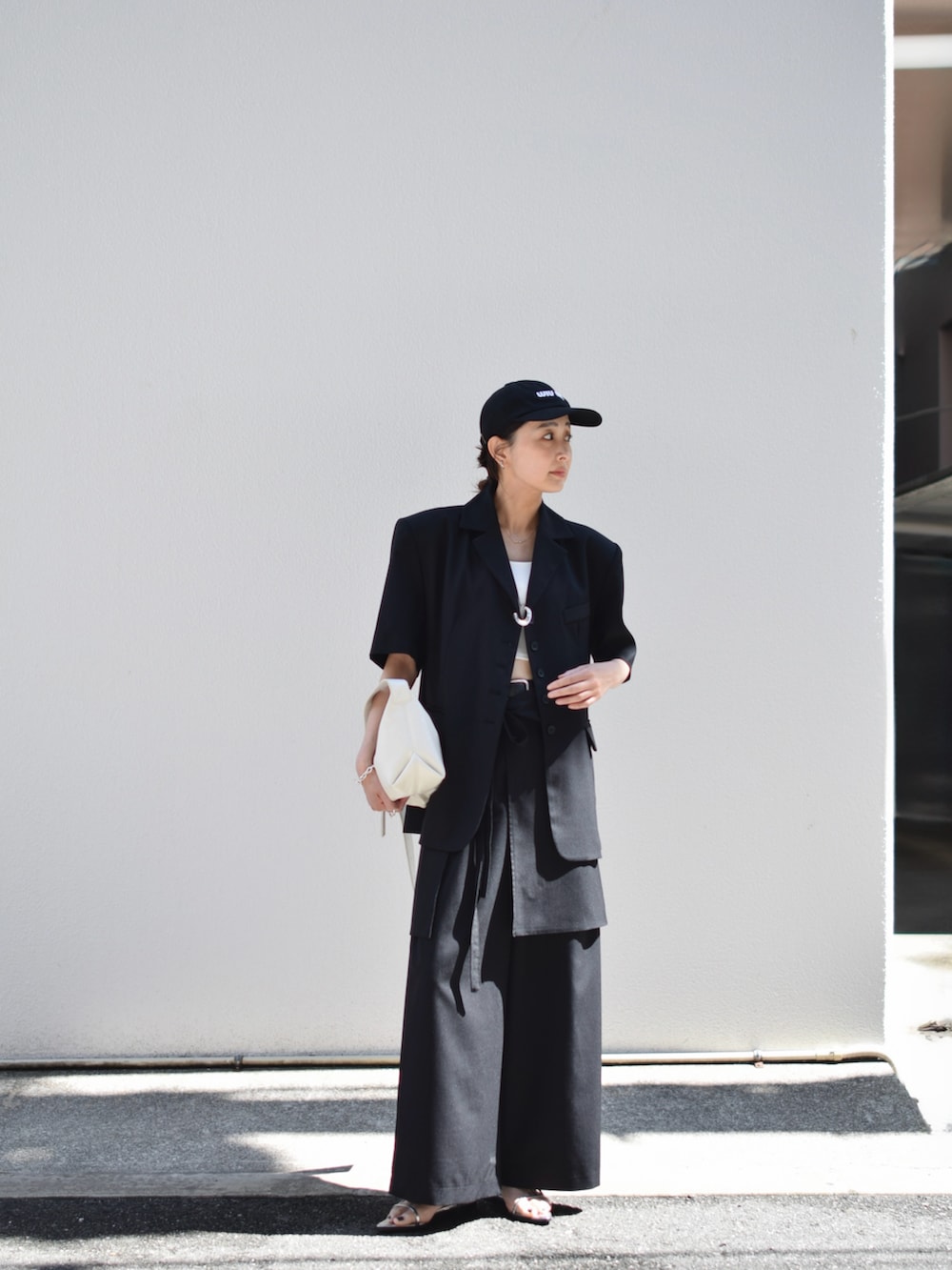 ブラック系のテーラードジャケット、ブラック系のスラックス、ホワイト系のショルダーバッグを着用したレディースの春コーディネートの5枚目の写真