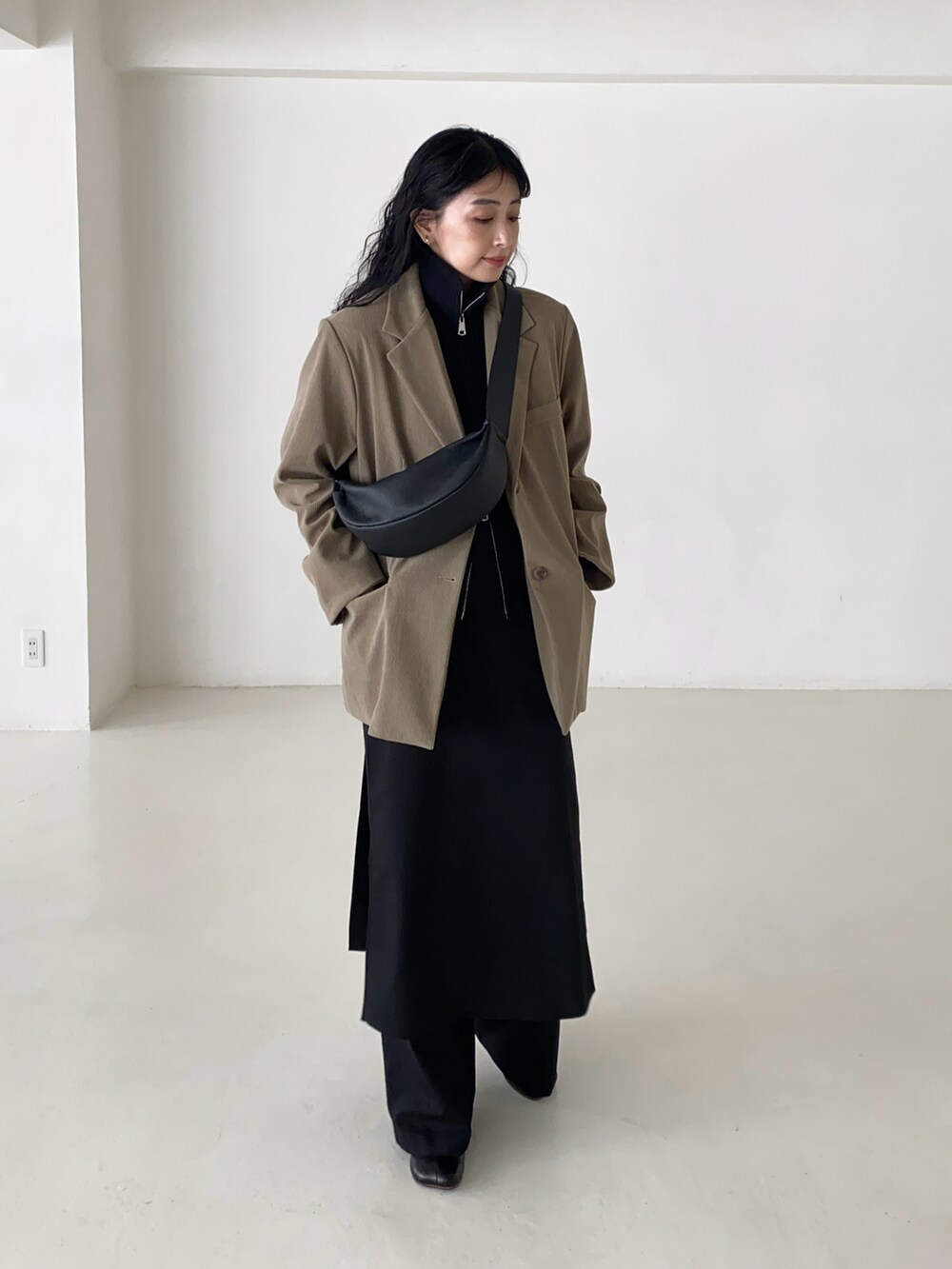 ベージュ系のテーラードジャケット、ブラック系のベスト、ブラック系のショルダーバッグを着用したレディースの冬コーディネートの2枚目の写真